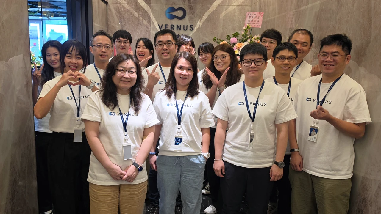 The Vernus AI team in front of the company logo wall